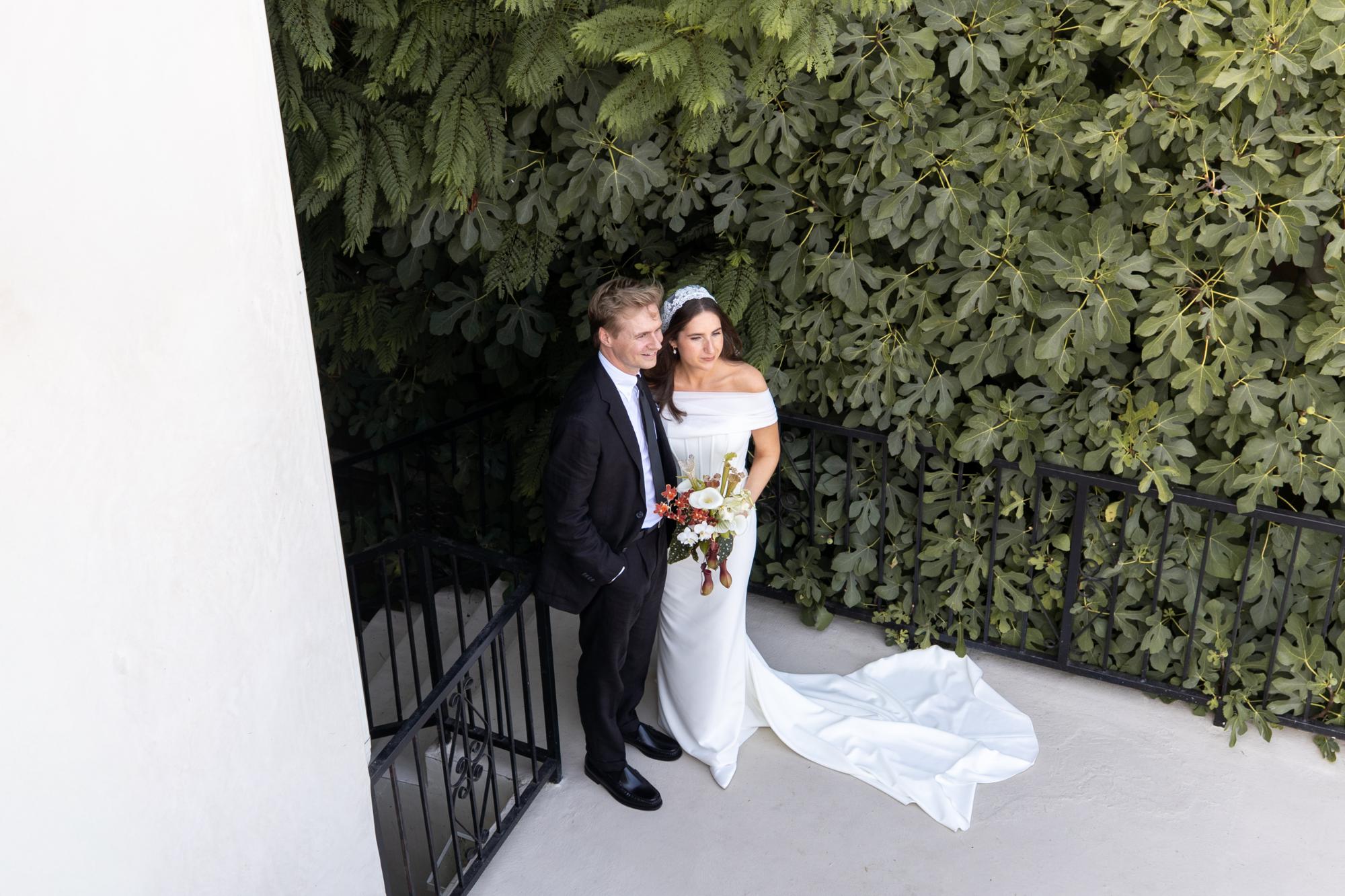 Bride and groom embracing pre - ceremony outdoors beside a lush green wall, captured by Fonseca Hansen Media.