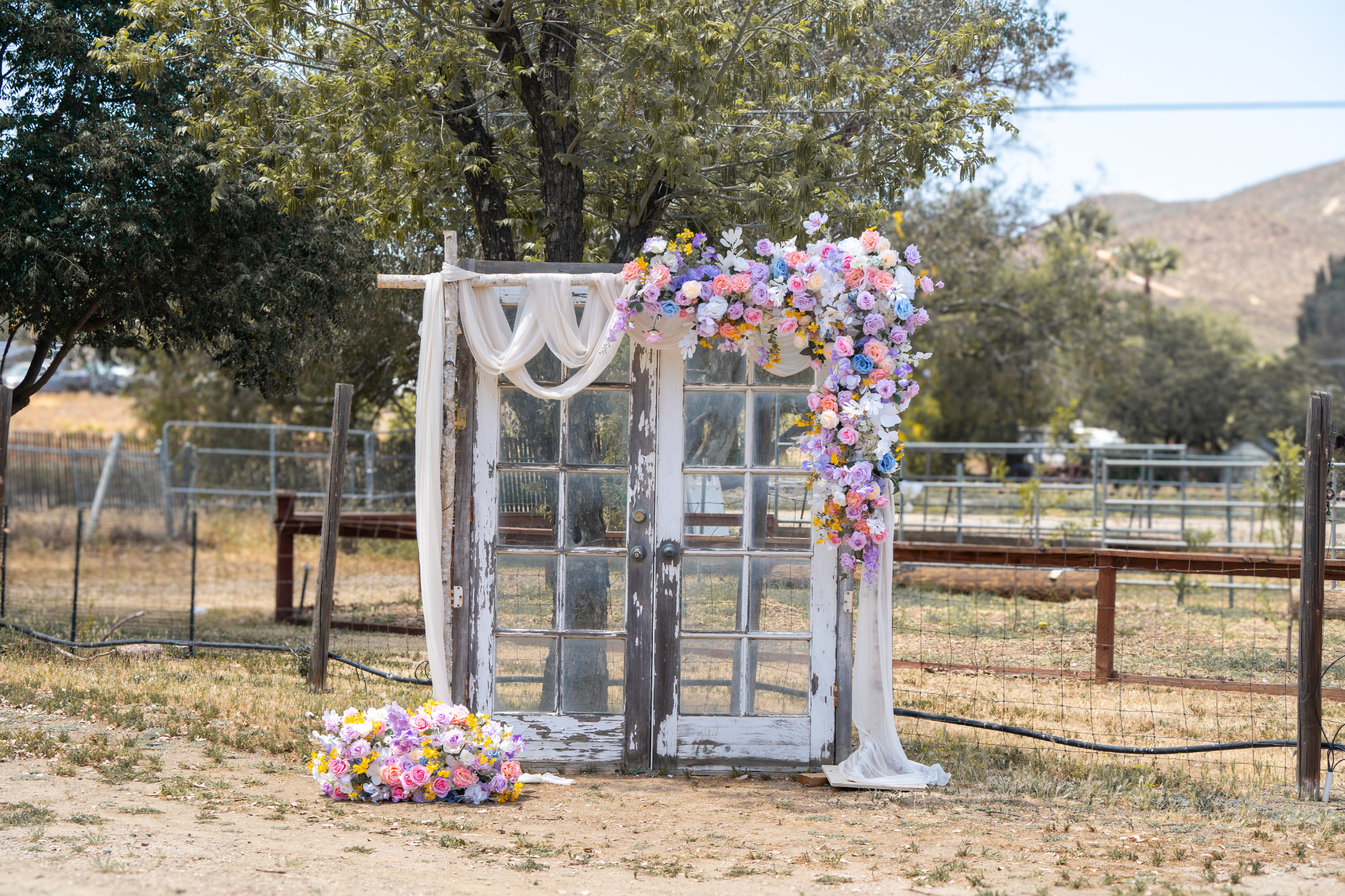 Colorful rustic floral wedding ceremony barn door set outdoors in a countryside venue, photographed by Fonseca Hansen Media.